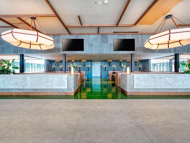 Moderne hotel lobby met grote lampen, zitgedeeltes en flatscreen-tv's.