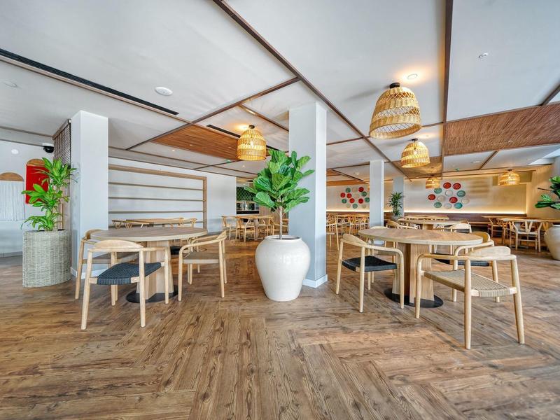 Licht, modern restaurant met houten meubels en groene planten.