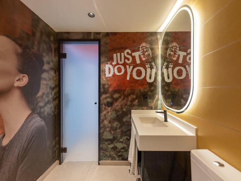 Moderní koupelna se osvětleným zrcadlem a nástěnnou malbou v hotelu.