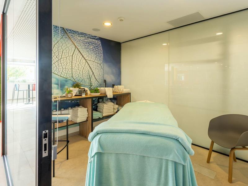 Léčební místnost s masážním stolem, židlí a regály v hotelovém spa.