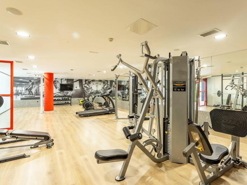 Světlá posilovna s moderním vybavením a dřevěnou podlahou.