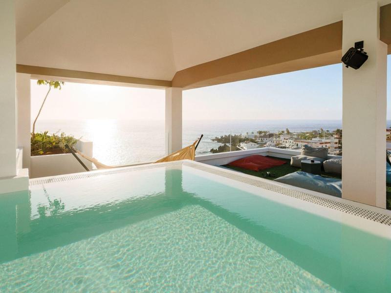 Vírivka s výhledem na město a moře při západu slunce.