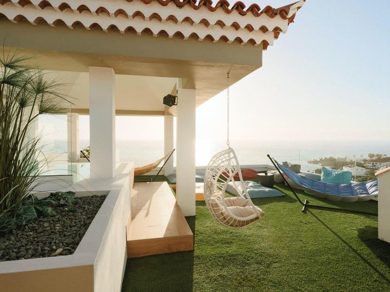 Moderní balkon s zavěšeným houpačkovým křeslem a lavičkou s výhledem na vodu