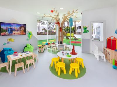 Bunter, moderner Kinderspielraum mit Spielzeug, kleinen Tischen und Stühlen, dekoriert mit Pflanzen.