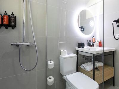 Modernes Badezimmer mit Dusche, Toilette, Waschbecken und beleuchtetem Spiegel.