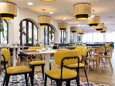 Restaurant lumineux avec des chaises jaunes et plusieurs lampes rondes au plafond.