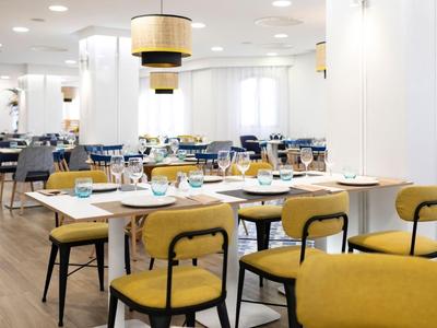Salle à manger moderne avec des chaises jaunes et des tables dressées dans un hôtel.