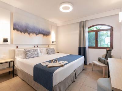 Modern eingerichtetes Hotelzimmer mit Doppelbett, Nachtischen und Fenster mit Blick nach draußen.