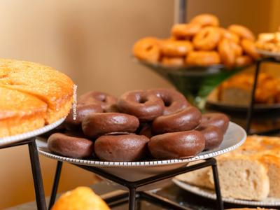 Variedad de productos horneados, incluidos donas de chocolate y pasteles, presentados en un buffet.