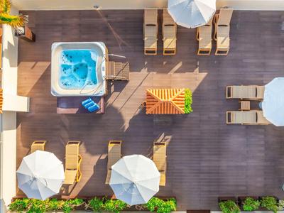 Vue aérienne d'une terrasse avec jacuzzi, transats et parasols.