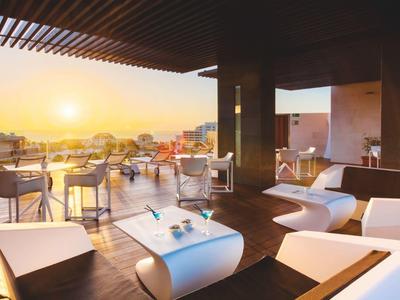 Terrasse sur le toit avec sièges modernes et vue sur coucher de soleil et la ville