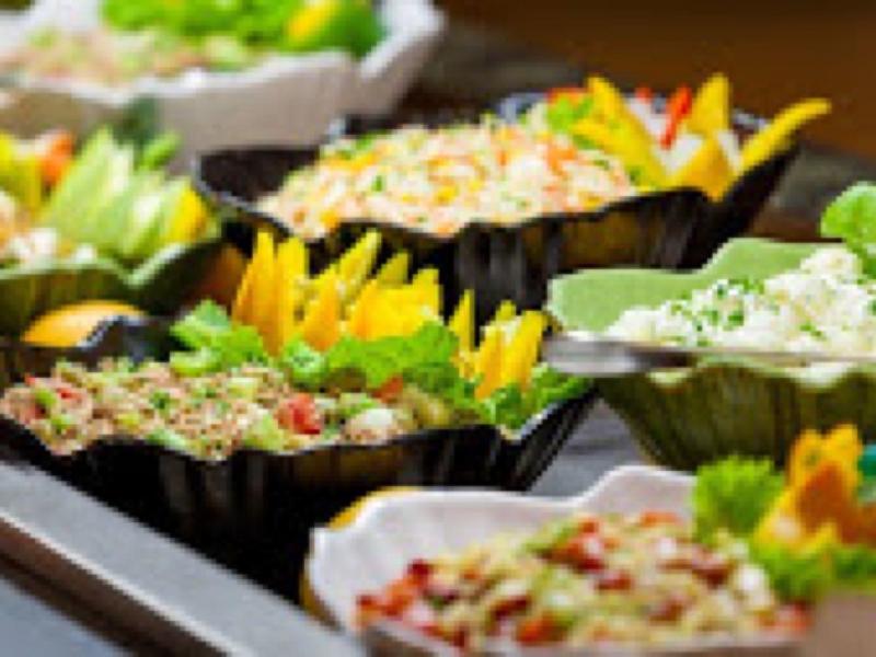 Buffet varié avec des salades fraîches et des légumes colorés dans des bols décoratifs.