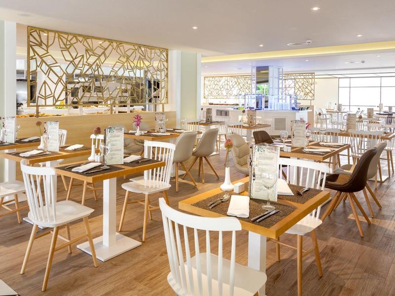 Restaurant lumineux et moderne avec sols en bois, chaises variées et tables claires.