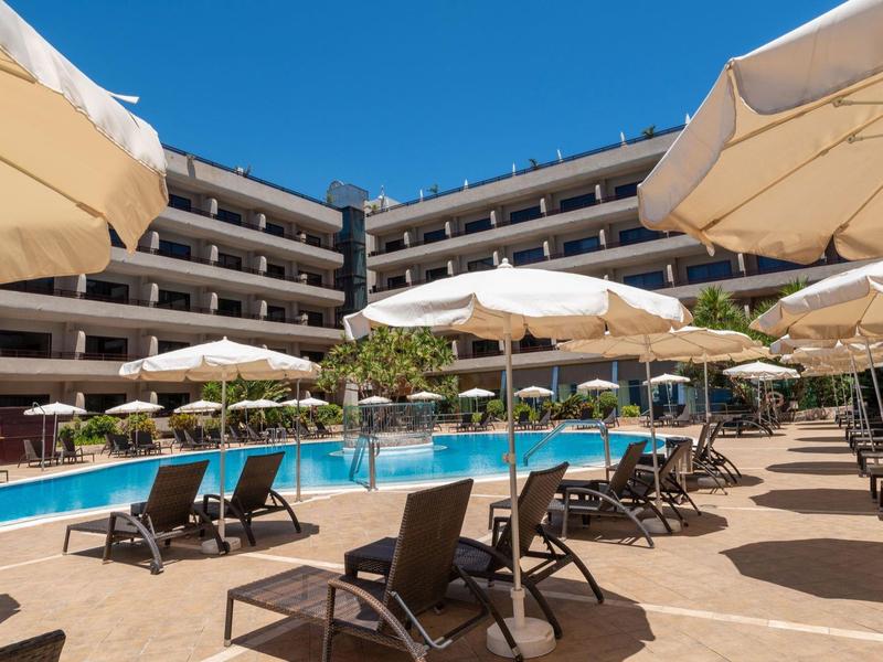 Nowoczesny kompleks hotelowy z basenem na zewnątrz i wieloma parasolami i leżakami