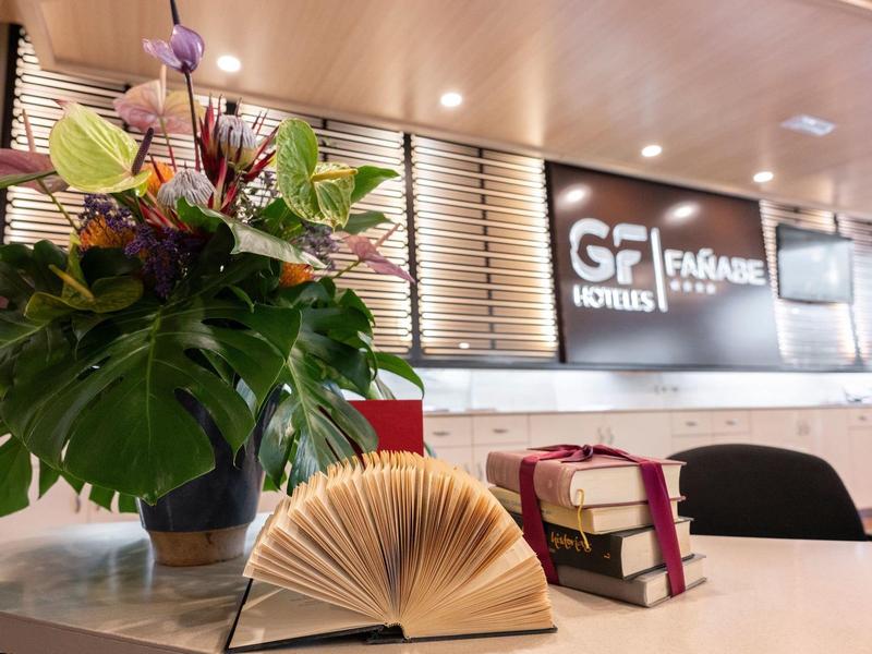 Recepcja z kwiatową dekoracją i ozdobną książką w GF Hotels Fagagna.