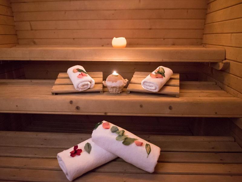 Przytulna sauna z drewnianym wnętrzem, świecą i dekoracyjnymi ręcznikami z kwiatami