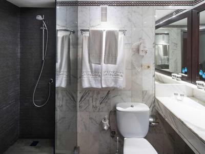 Modernes Badezimmer mit weißer Toilette, Marmorwand, Glasdusche und großem Spiegel.
