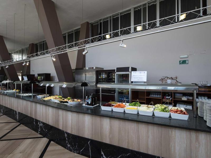 Station de buffet moderne avec légumes frais et salades dans une salle à manger lumineuse.