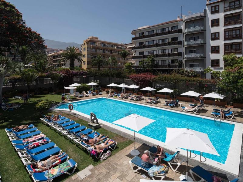 Espace extérieur de l'hôtel avec piscine, transats et parasols par temps ensoleillé