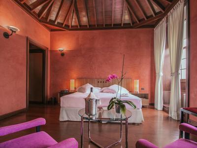 Przytulny pokój hotelowy z różowymi ścianami, drewnianym stropem i nowoczesnym wyposażeniem.