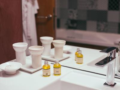 Jasna łazienka z białymi akcesoriami, małymi buteleczkami i lustrem.