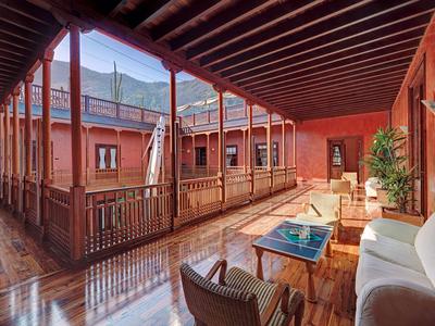 Ein offener Balkon mit Holzboden und Sitzgelegenheiten in einem Gebäude mit roten Wänden.