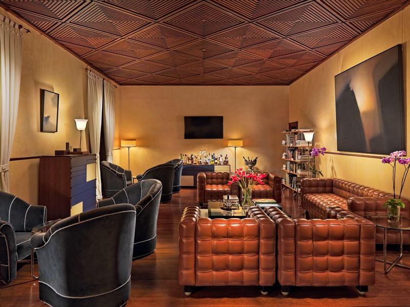 Przytulny salon hotelowy z skórzanymi sofami, fotelami, sztuką na ścianach i delikatnym oświetleniem.