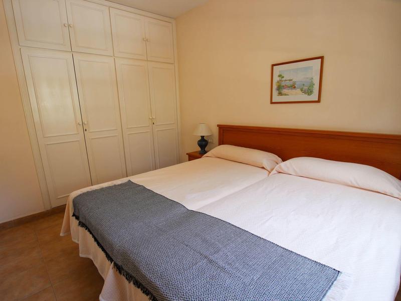 Chambre d'hôtel simple avec un lit double, murs clairs et grande armoire encastrée.