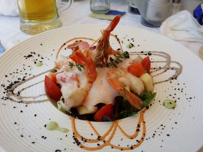 Shrimp with vegetables and sauce served decoratively on a white plate.