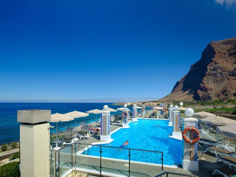 Infinity pool overlooking the sea and mountains under a sunny sky