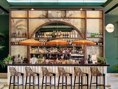 Elegante Bar mit sechs Holzstühlen, kupferfarbenen Lampen und einer vielfältigen Spirituosenauswahl.