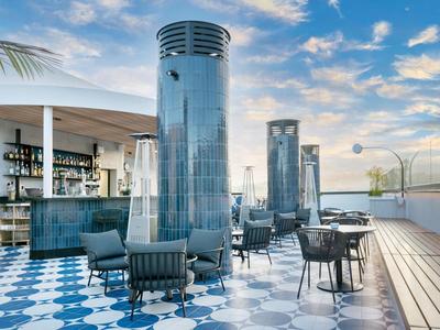 Moderne Dachterrasse mit Heizstrahlern, Stühlen und Tischen bei Sonnenuntergang.