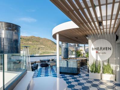 Moderne Dachterrasse mit blau-weißen Fliesen und Blick auf die Berge bei klarem Himmel.