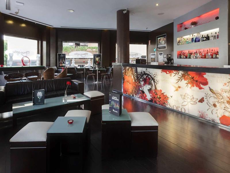 Interior moderno de bar de hotel con mostrador iluminado y asientos negros.