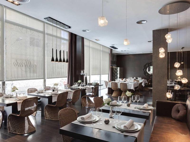Restaurante moderno con grandes ventanas, muebles de madera elegantes y iluminación con estilo.