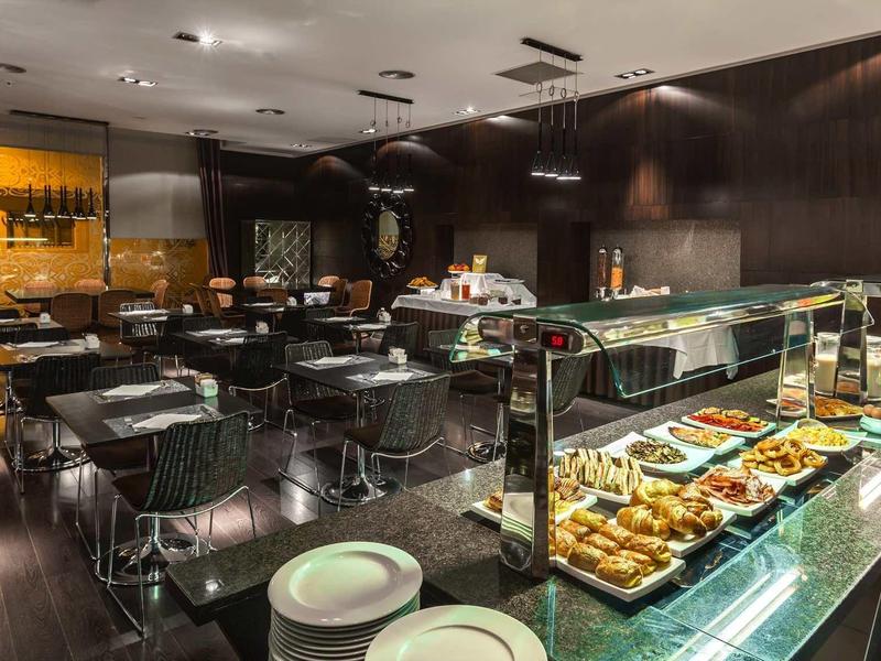 Restaurante moderno con área de buffet, madera oscura y asientos elegantes.