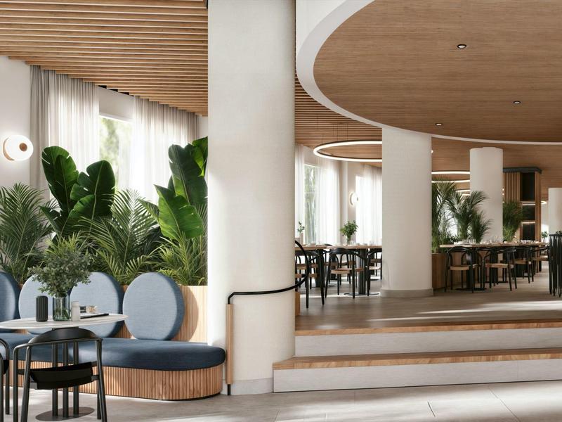 Modernes Hotel-Lobby mit Pflanzen, runden Sitzgelegenheiten und Holzdecke.
