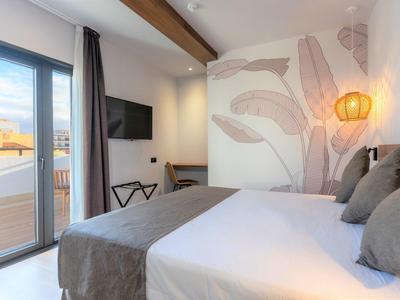 Chambre d'hôtel moderne avec lit double, balcon et décoration murale.