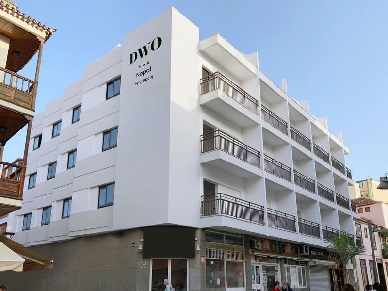 Hôtel moderne avec façade blanche et balcons sous un ciel bleu clair.