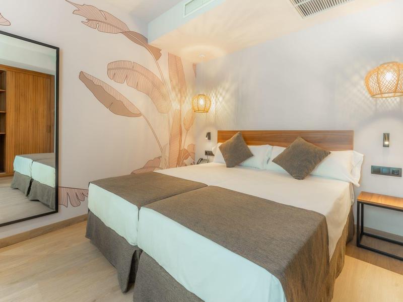 Chambre moderne avec lit double, décoration murale dorée et grand miroir.