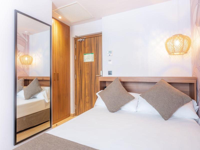 Chambre d'hôtel moderne avec lit double, deux oreillers bruns et porte en bois.