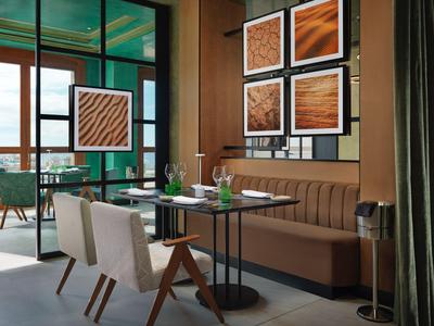 Moderne eetruimte in hotel met bruine tinten en decoratieve wandkunst.
