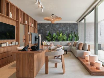 Moderne woonkamer met houten meubels, grijze stenen muur en grote ramen met uitzicht naar buiten.