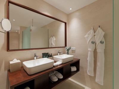Modernes Hotelbadezimmer mit zwei Waschbecken, Spiegel, Bademänteln und Handtüchern.