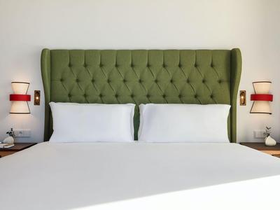 Modernes Hotelzimmer mit grünem gepolstertem Kopfteil und weißer Bettwäsche.