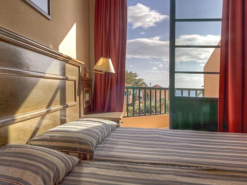 Světelná ložnice s balkonem a výhledem na oblohu a stromy.