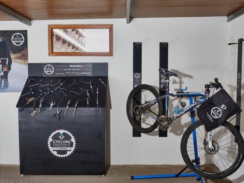 Stazione di lavaggio biciclette interna con bici e supporti a muro sotto un soffitto di legno