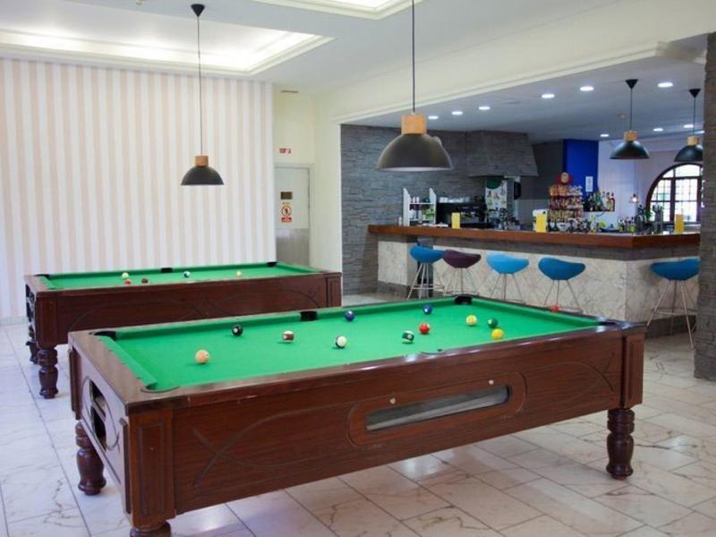Area giochi interna con due tavoli da biliardo e un bancone bar con sgabelli sullo sfondo.