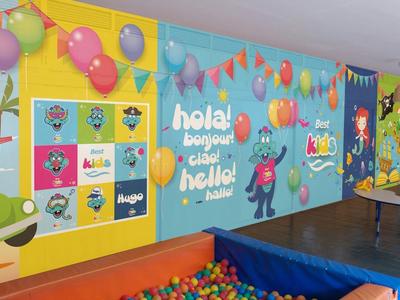 Parete colorata della sala giochi con mappa del mondo, palloncini e piscina di palline in area ricreativa.