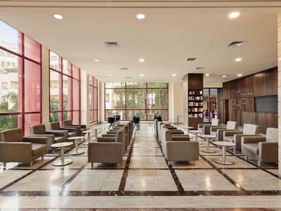 Großer, moderner Hotellobby-Bereich mit Sofas, Sesseln und großen Fenstern.